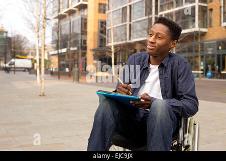 wheelchair bound man looking thoughtful with folders and a pen Stock Photo