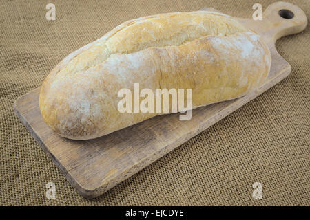 Bread on Bread Board on Burlap Background Stock Photo