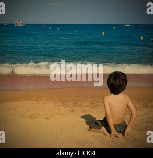 boy on the beach watching at the sea Stock Photo