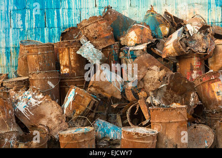Old pile of rusty paint cans against wall Stock Photo