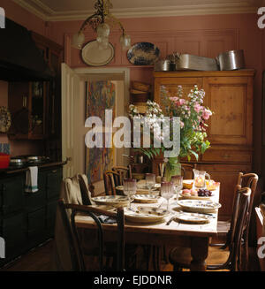 Vase of summer flowers on old pine table set for lunch in nineties kitchen Stock Photo