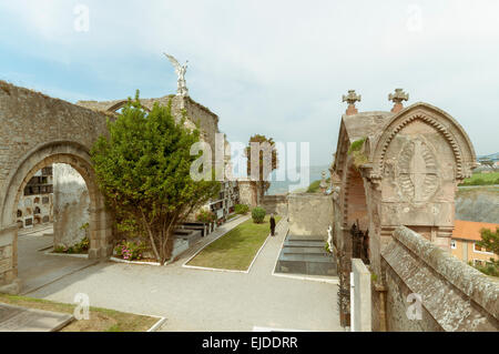 Sculpture of a guardian angel on a stone arch, with a sword in the cemetery of Comillas. Cantabria - Spain Stock Photo
