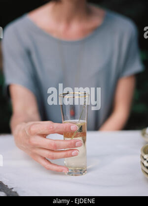 A woman holding a glass of champagne seated at a table. Stock Photo