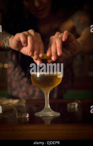 A woman's hands squeezing a slice of lemon over a cocktail glass. Stock Photo