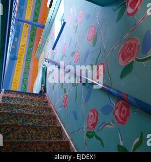 Pink roses painted on blue wall beside colorfully painted staircase in nineties cottage Stock Photo