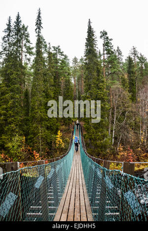 Two hikers crossing a suspension bridge Stock Photo