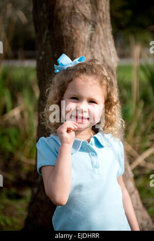 Young girl leaning against oak tree, portrait