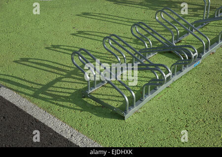 Stainless steel bicycle empty racks over green asphalt surface Stock Photo