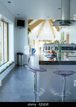 Perspex+chrome stools at breakfast bar in modern open plan kitchen Stock Photo