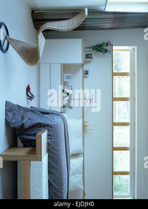 Tom Dixon 'S'chair in modern bedroom with gray quilt on fitted bed Stock Photo