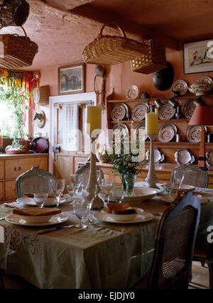 Table set for lunch in cluttered pink cottage kitchen Stock Photo