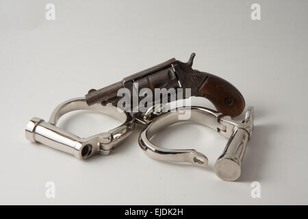 old handcuffs with locking screw English style and revolver derringer Stock Photo