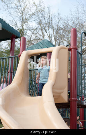 Young girl goes down slide at park playground Stock Photo