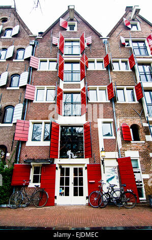 Red shuttered houses alongside a canal in Amsterdam. Formerly warehouses, these are now converted to residences. Stock Photo