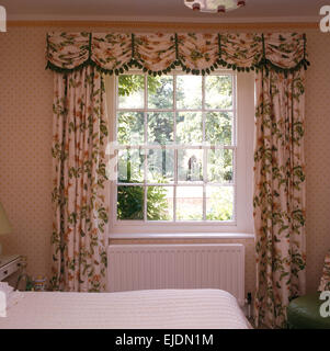 Floral curtains and pelmet designed by Henrietta Spencer-Churchill on window in country bedroom Stock Photo