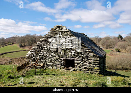 Traditional old agricultural implement hay rake outside a stone barn in countryside in Snowdonia, North Wales, UK, Britain Stock Photo