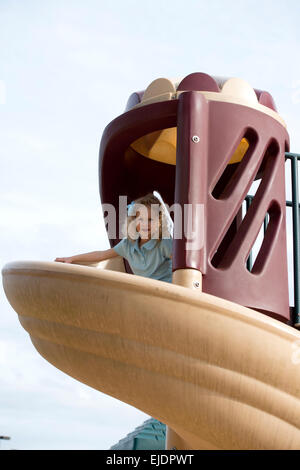 Four year old girl going down slide on park playground Stock Photo