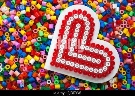 plastic multi coloured Hama beads with red and white heart completed template for crafts Stock Photo