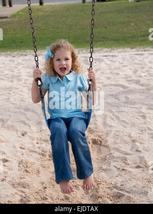 Four Year old girl swinging at park playground Stock Photo