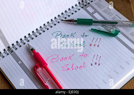 Notebook with metal spiral and pencil, opened at one page that says  BACK TO SCHOOL in colors green and pink. Stock Photo