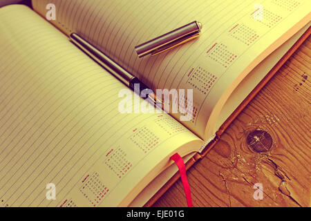 Open diary with one fountain pen in it, placed on a wood table. Vintage processing. Stock Photo