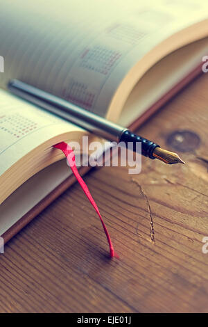 Open diary with one fountain pen in it, placed on a wood table. Vintage processing. Stock Photo