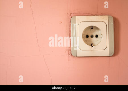Old and dirty white electricity outlet on pink wall Stock Photo