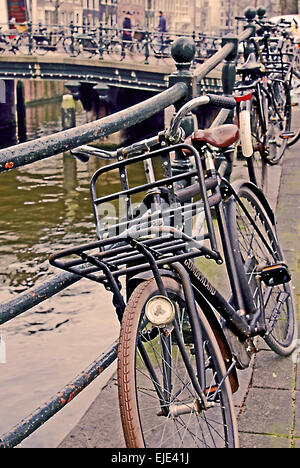 Bikes leant against railings on a bridge over one of Amsterdam's many canals Stock Photo