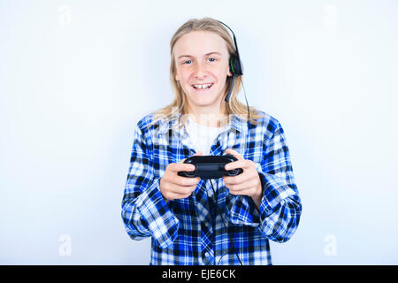 A teen boy playing video games against gray background Stock Photo