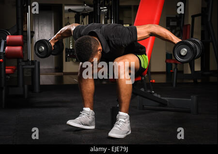 Young man doing Seated Bent Over Dumbbell Reverse Fly workout in gym ...