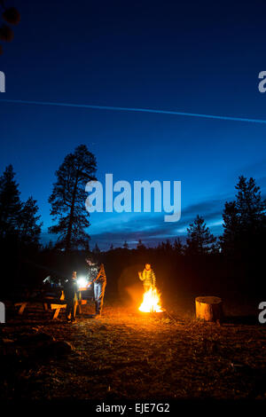 Family Sitting Around a Fire at Night  While Camping Stock Photo