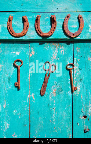 old rusty historical key and luck symbol horseshoe on wooden green farm wall Stock Photo