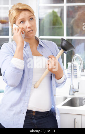 Frustrated Woman Calling Plumber To Fix Blocked Sink At Home Stock Photo