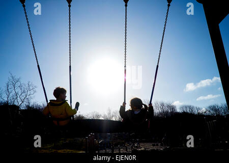 Childeren on a swing at the playground Stock Photo