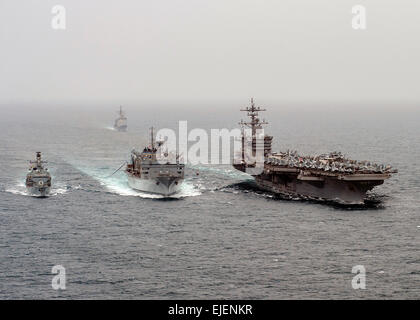 US Navy nuclear aircraft carrier USS Carl Vinson and the Royal Navy destroyer HMS Kent (left) conduct a replenishment-at-sea with the Military Sealift Command combat support ship USNS Rainier (center) March 18, 2015 in the Arabian Sea. The group is deployed for Operation Inherent Resolve striking ISIS targets in Iraq and Syria. Stock Photo