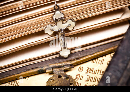 crucifix with jesus hanging on sides of opened historic bible, Stock Photo