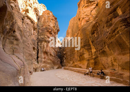 PETRA, JORDAN - OCT 12, 2014: Tourists are sitting an resting in 'the Siq'.'The Siq' is a narrow gorge who leads visitors into P Stock Photo