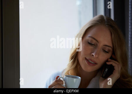 Young woman talking on the phone and drinking coffee Stock Photo