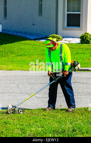 Highway Maintenance worker wearing yellow safety apparel  uses a gas-powered sod cutter in preparation for removal Stock Photo