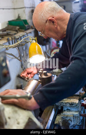 Engineer and vintage car maker working on his lathe in the workshop