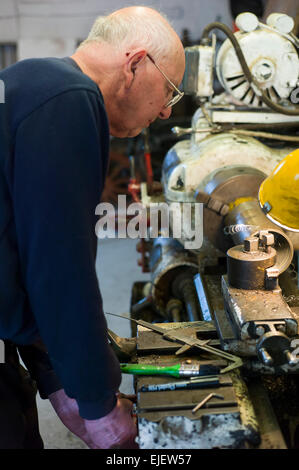 Engineer and vintage car maker working on his lathe in the workshop