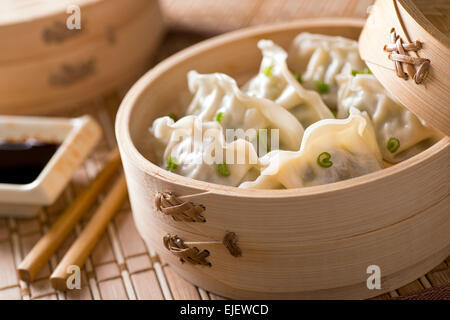 Dim sum with leeks, meat, and green onions in a bamboo steamer. Stock Photo