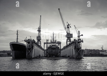 Floating dry dock with old ship under repair inside, retro stylized black and white photo, front view Stock Photo