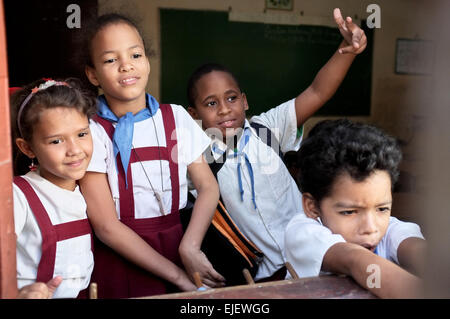 Children in uniforms look out a school window in Havana, Cuba. Stock Photo