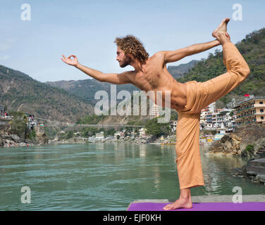 A man practicing yoga by the river Ganges in Rishikesh India Stock Photo