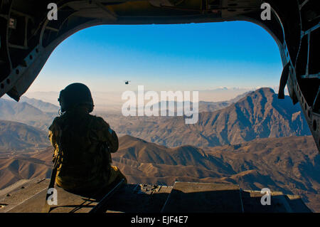 U.S. Army Spc. Devon Boxa from San Angelo, Texas, a member of Company B, 7th Battalion, 158th Aviation Regiment, admires the Afghan landscape out the back door of a CH-47D Chinook helicopter as another Chinook follows. The choppers were flying from Kabul to Jalalabad Dec. 17. Stock Photo