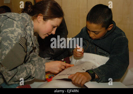 080225-F-5090B-001 - BAGRAM AIRFIELD, Afghansitan, Army Sgt. Heather Slater, deployed from the 367th Military Police Company, Horsham, Pa., shoes an Afghan boy at how use crayons and a coloring book Feb. 25 at the Egyptian Hospital here. Slater and several other servicemembers from the 724th MP Battalion visits inpatients at the hospital every Sunday.  Senior Airman James Bolinger Stock Photo