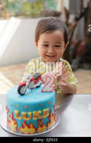Delighted toddler boy clapping after blowing out the candle on his birthday cake Stock Photo