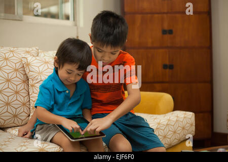 Two boys playing on a digital tablet Stock Photo