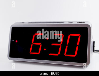 A retro looking silver digital alarm clock at midnight in red lights ...